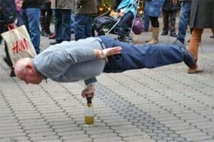 Old man balancing on wine bottle